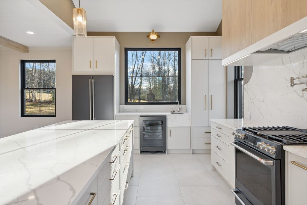 Custom Maine kitchen featuring a white oak island, quartz countertops, white cabinetry, and layered lighting.